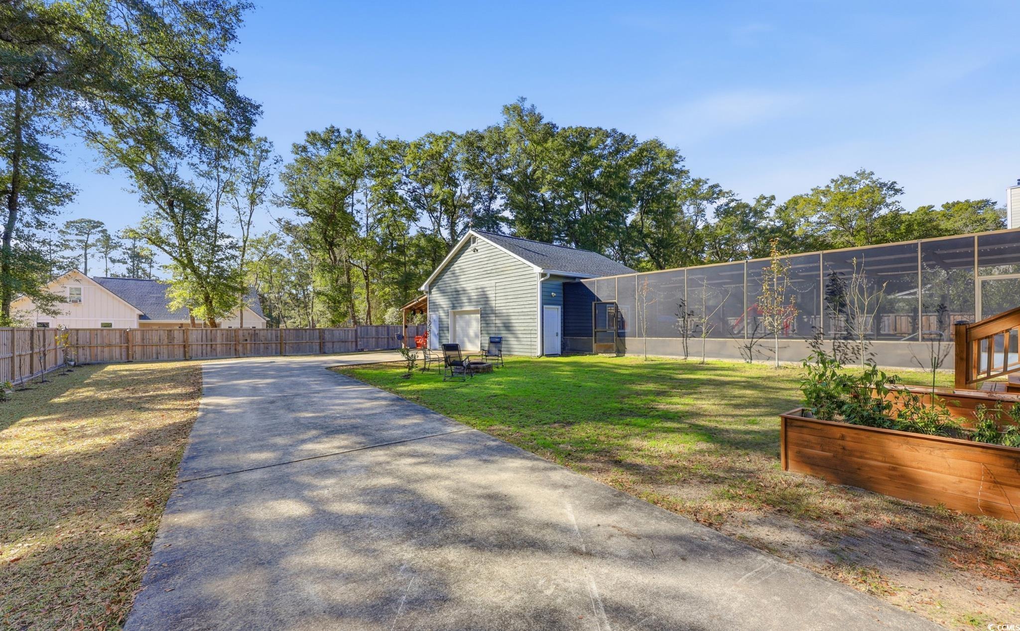 78 Wicklow Way Pawleys Island, SC 29585 - Photo 29 of 37 Fenced backyard featuring an outbuilding, a vegetable garden, and a sunroom