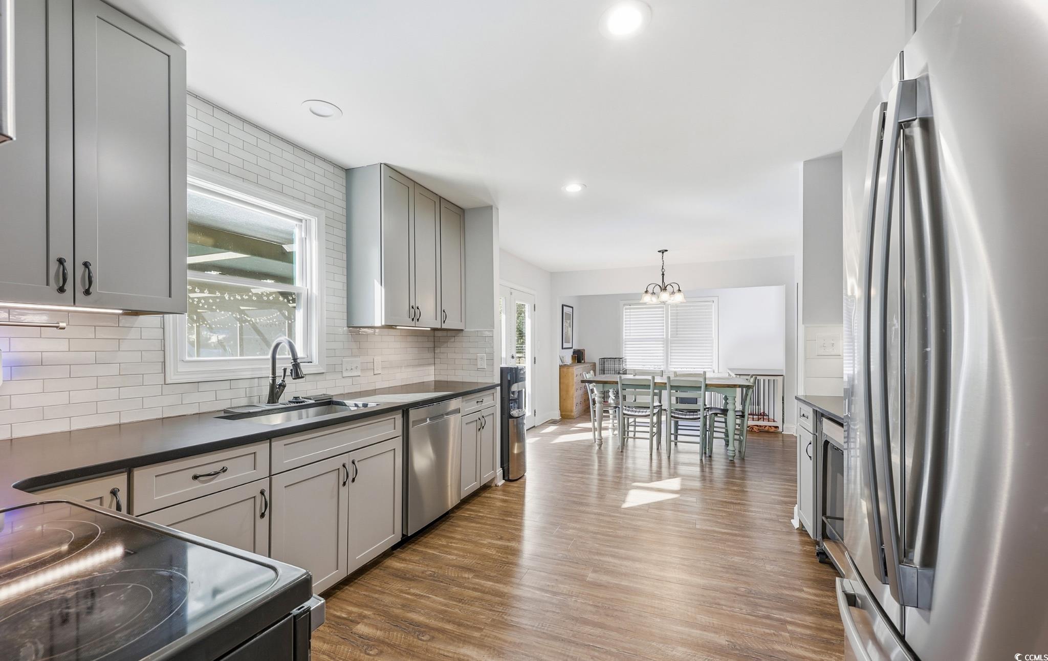 78 Wicklow Way Pawleys Island, SC 29585 - Photo 9 of 37 Kitchen featuring appliances with stainless steel finishes, gray cabinets, dark countertops, dark wood-style flooring, and pendant lighting