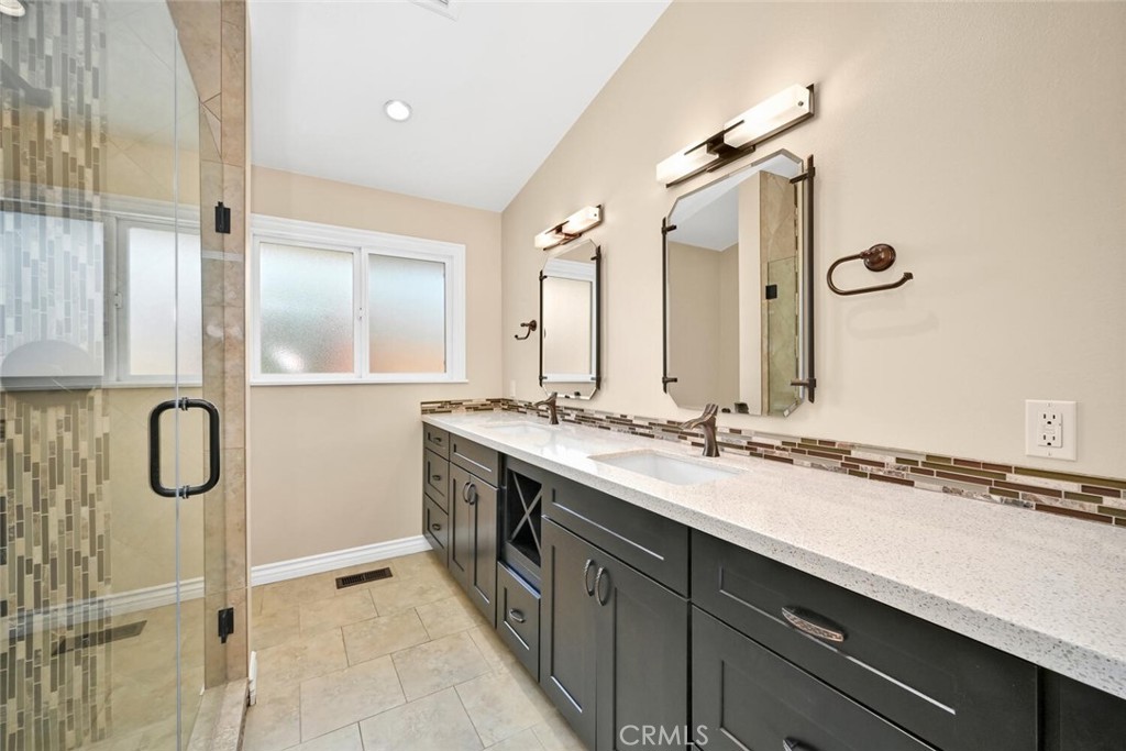 5531 Rockledge Drive Buena Park, CA 90621 - Photo 33 of 64 a bathroom with a granite countertop sink a mirror a vanity and a shower