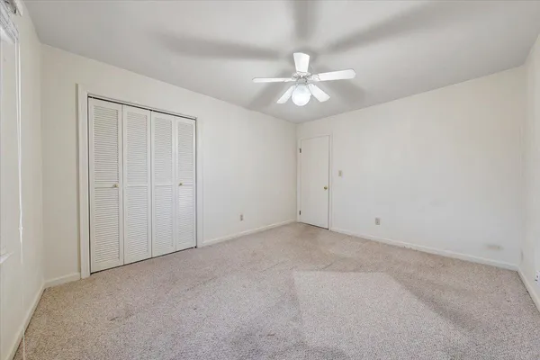 an empty room with a chandelier fan and closet area