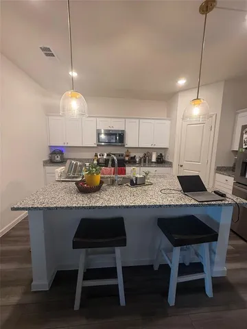a kitchen with kitchen island granite countertop a table chairs a sink and a stove