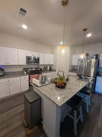 a kitchen with stainless steel appliances granite countertop a sink a stove and chairs