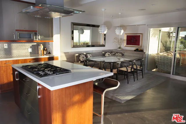 a kitchen with a stove a sink dishwasher and a dining table with wooden floor