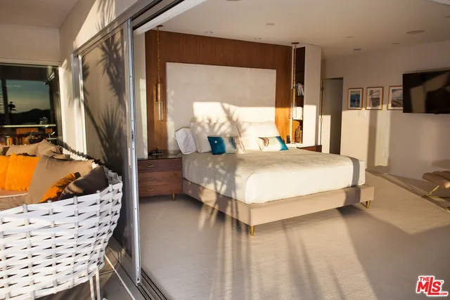 a bedroom with a bed a flat screen tv and dresser