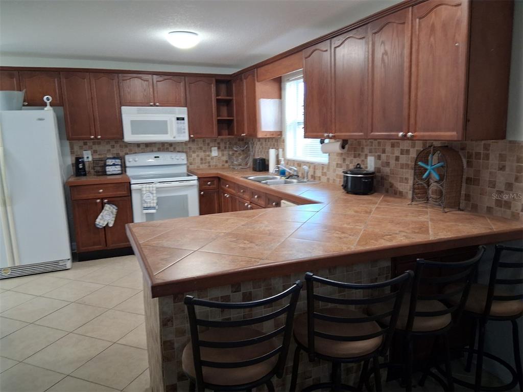 14982 Edgewater Circle Hudson, FL 34667 - Photo 5 of 22 a kitchen with a table chairs microwave and cabinets