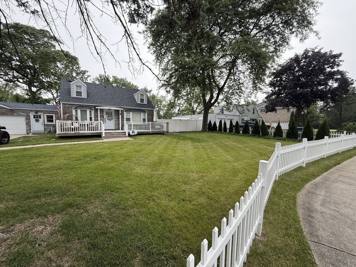 a view of a house next to a big yard and large trees