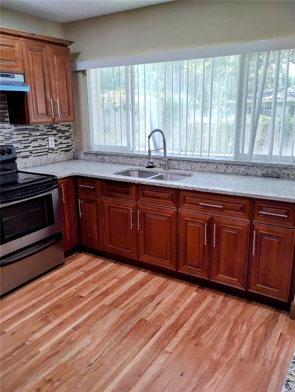 11721 Raintree Drive Tampa, FL 33617 - Photo 3 of 12 a kitchen with granite countertop wooden cabinets a sink and a window