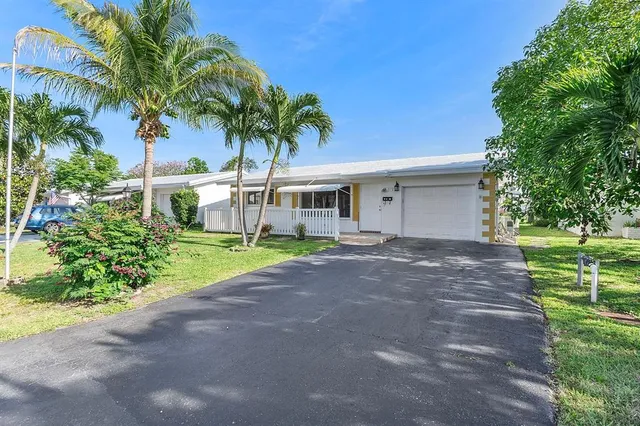 a view of a house with a yard and palm trees