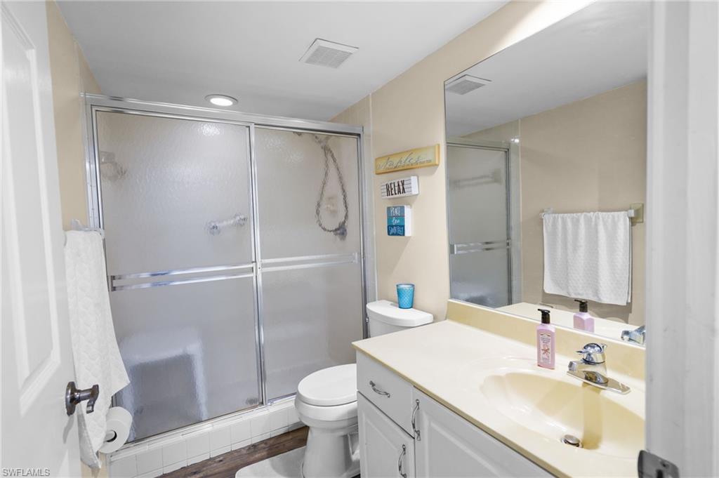 601 Augusta Boulevard, Unit 10 Naples, FL 34113 - Photo 16 of 27 Full bathroom featuring vanity, a shower stall, and dark wood-type flooring