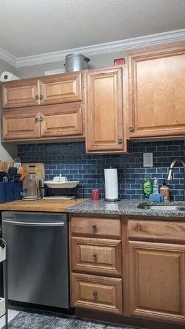 a kitchen with granite countertop a sink and a white wooden cabinets
