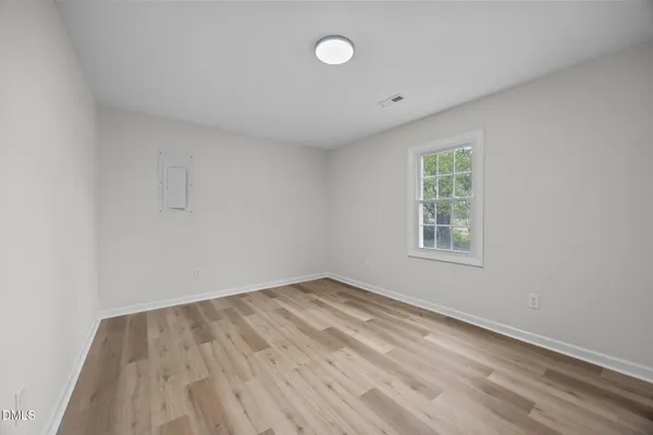an empty room with wooden floor and windows