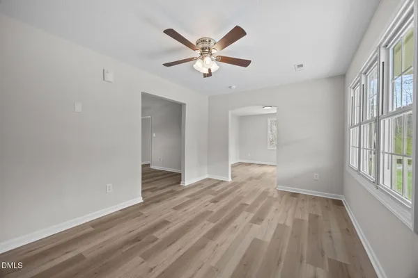 a view of an empty room with window and wooden floor