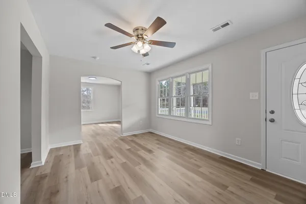 a view of an empty room with wooden floor and a window