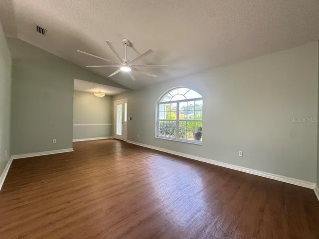an empty room with wooden floor and windows