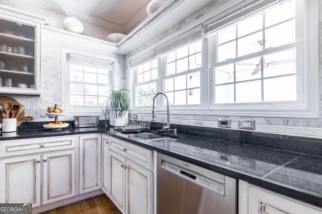 a kitchen with stainless steel appliances white cabinets and a large window