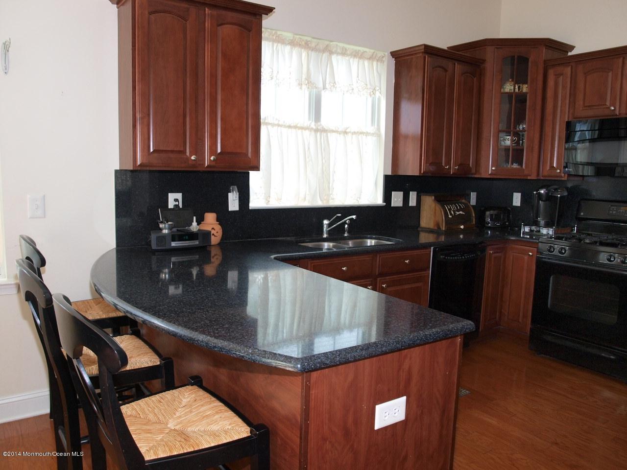 80 Pancoast Road Waretown, NJ 08758 - Photo 8 of 32 a kitchen with granite countertop a sink a stove and wooden cabinets