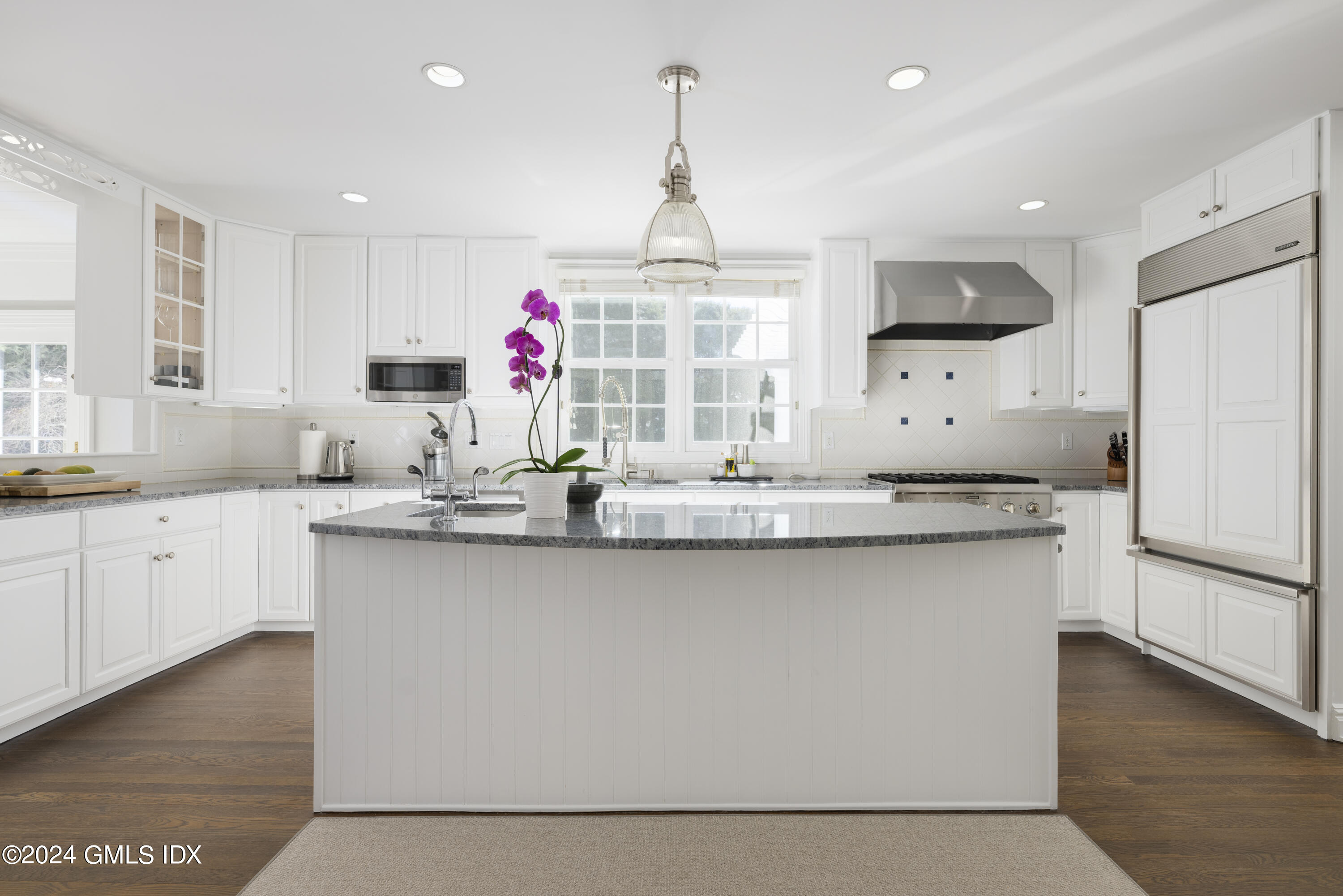 17 Rustic View Road Greenwich, CT 06830 - Photo 7 of 26 a kitchen with granite countertop a white refrigerator a sink dishwasher and a dining table with wooden floor