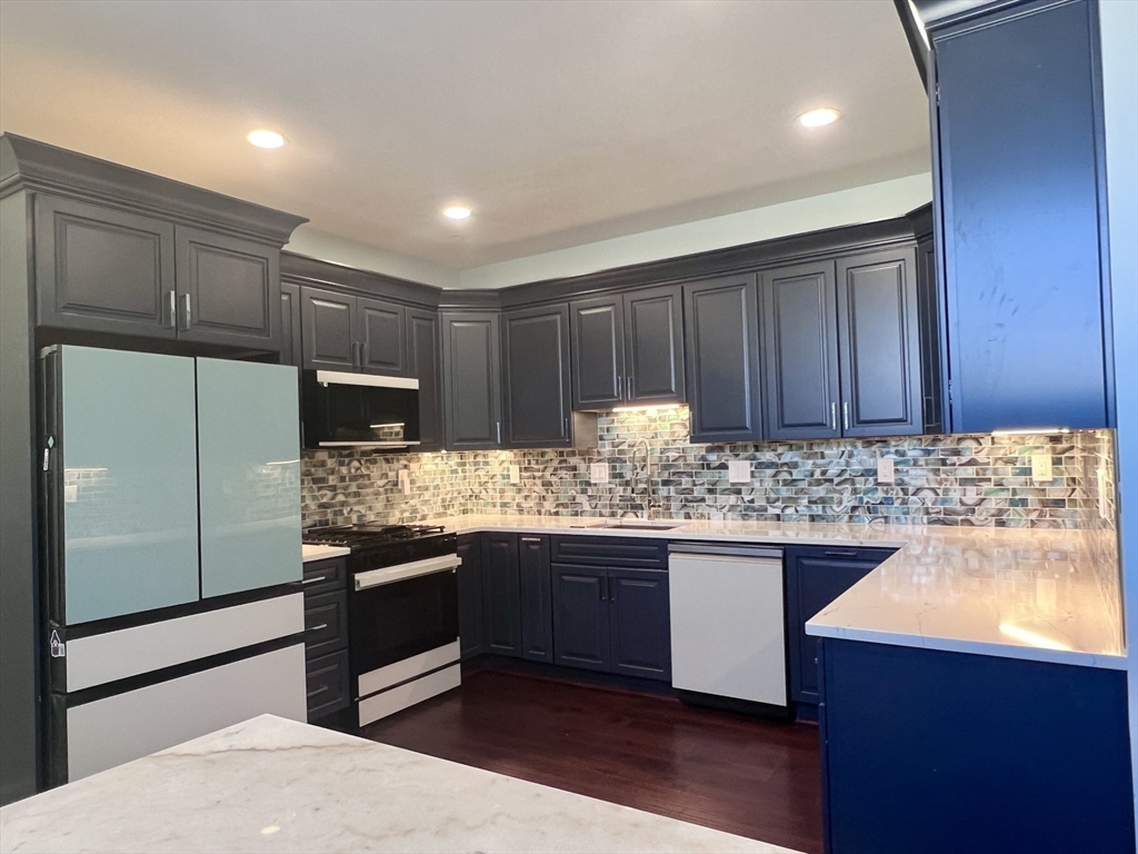 202 Broadway, Unit 33 Lawrence, MA 01840 - Photo 2 of 13 a kitchen with kitchen island granite countertop wooden cabinets and stainless steel appliances