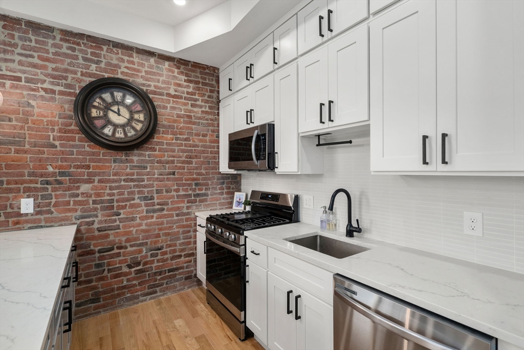 152 Marion Street, Unit 6L Boston, MA 02128 - Photo 8 of 22 a kitchen with stainless steel appliances a stove a sink and a microwave