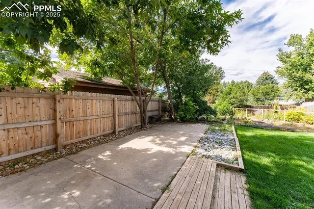 a view of backyard with wooden fence and large trees
