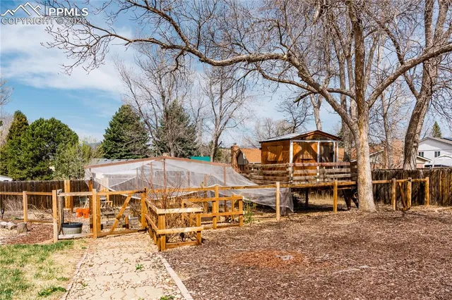 front view of a house with a large tree and wooden fence