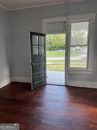 a view of an empty room with a window and wooden floor