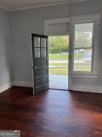a view of an empty room with a window and wooden floor