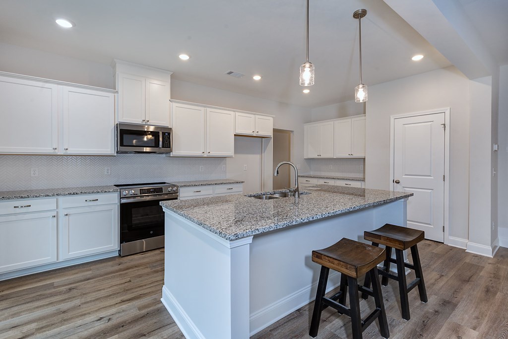 8711 McKee Road Upatoi, GA 31829 - Photo 11 of 45 a kitchen with stainless steel appliances granite countertop a sink a stove a microwave a island with a dining table and chairs