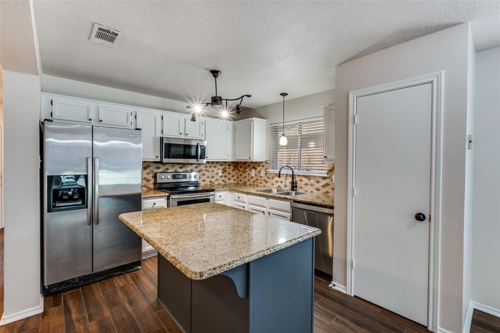 2606 Whetstone Drive Corinth, TX 76210 - Photo 3 of 28 a kitchen with granite countertop a refrigerator a sink a stove and cabinets
