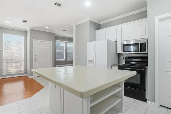 a kitchen with a refrigerator a stove a microwave and white cabinets