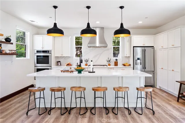 a kitchen with stainless steel appliances granite countertop a stove a refrigerator a oven a dining table and chairs with wooden floor