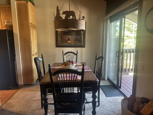 25 Lee Road, Unit 106 Mammoth Lakes, CA 93546 - Photo 3 of 16 Dining area featuring a wood-finish table, a sliding glass door to a deck, and an adjacent kitchen space with light wood cabinetry