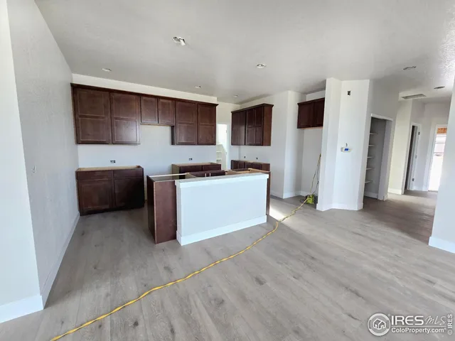 a kitchen with stainless steel appliances a sink a stove a microwave a refrigerator a cabinets and wooden floor