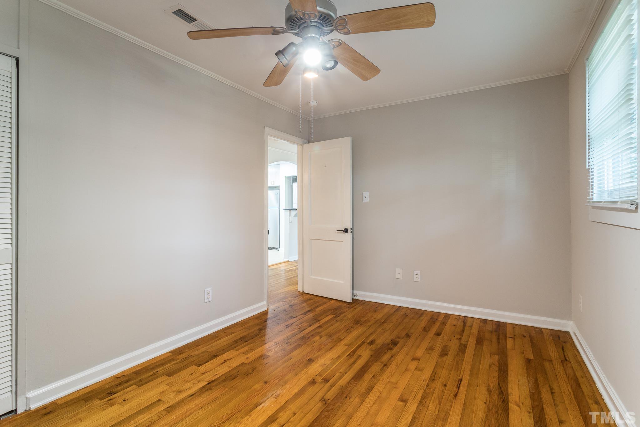 2620 McNeil Street, Unit 2620 Raleigh, NC 27608 - Photo 16 of 23 an empty room with wooden floor chandelier fan and windows