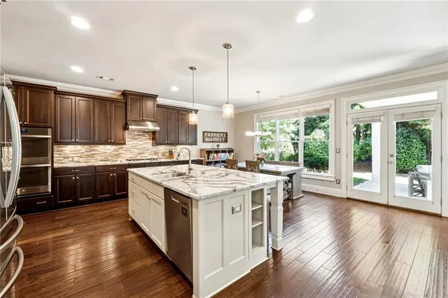 a kitchen with kitchen island granite countertop a stove a sink a center island and wooden floor