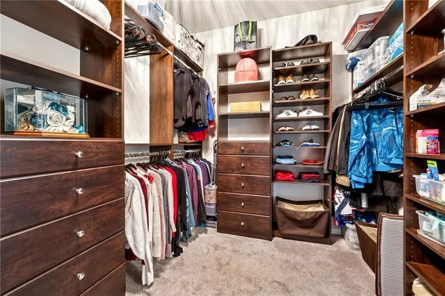 a view of walk in closet with clothes and shoes