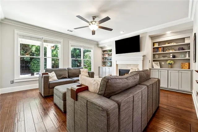 a living room with furniture a flat screen tv and a floor to ceiling window with wooden floor
