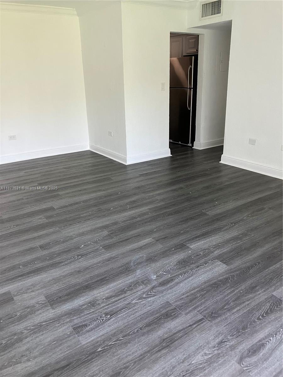 7256 Southwest 94th Place, Unit A1 Miami, FL 33173 - Photo 2 of 7 a view of an empty room with wooden floor and a window