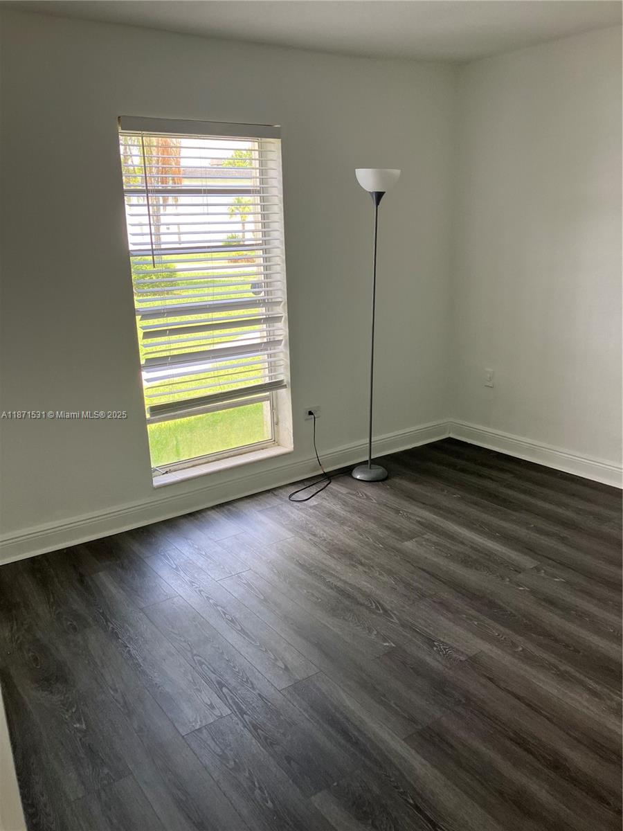 7256 Southwest 94th Place, Unit A1 Miami, FL 33173 - Photo 6 of 7 an empty room with wooden floor and windows