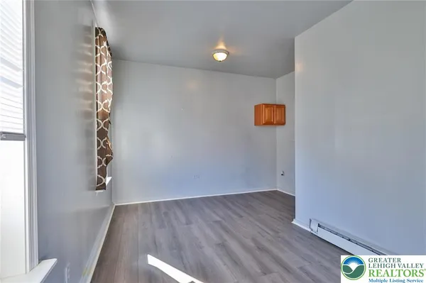a view of an empty room with wooden floor and windows