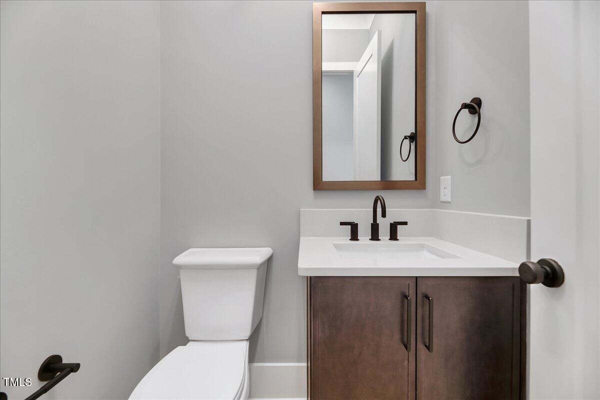 811 Maple Berry Lane, Unit 106 Raleigh, NC 27607 - Photo 8 of 30 a bathroom with a toilet sink vanity and mirror
