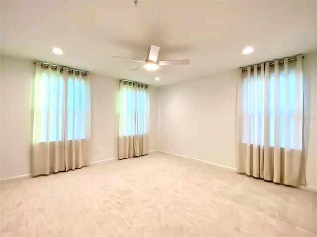 an empty room with windows and a chandelier fan