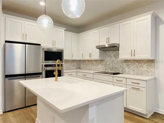 a kitchen with stainless steel appliances a stove a sink and white cabinets