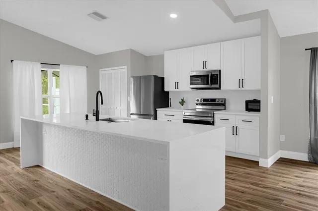 a kitchen with white cabinets and stainless steel appliances