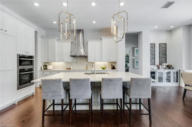 a kitchen with stainless steel appliances kitchen island granite countertop a stove a sink a refrigerator and a dining table with wooden floor