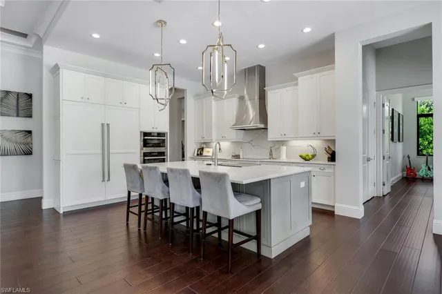 a large white kitchen with a large island oven a stove and a sink with wooden floor