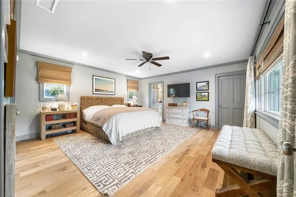 a spacious bedroom with a large bed a chandelier and windows