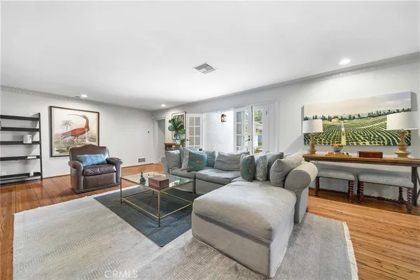 a spacious bedroom with a bed a couch and a dresser with wooden floor