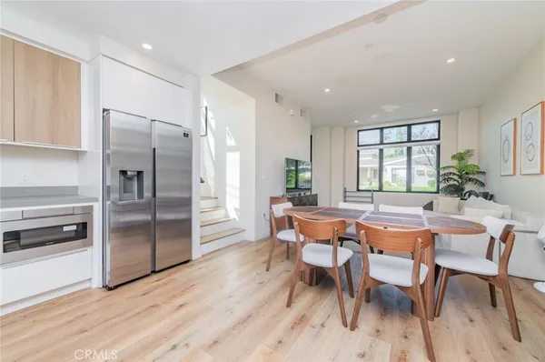a dining room with stainless steel appliances a table and chairs