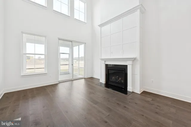 an empty room with wooden floor fireplace and windows